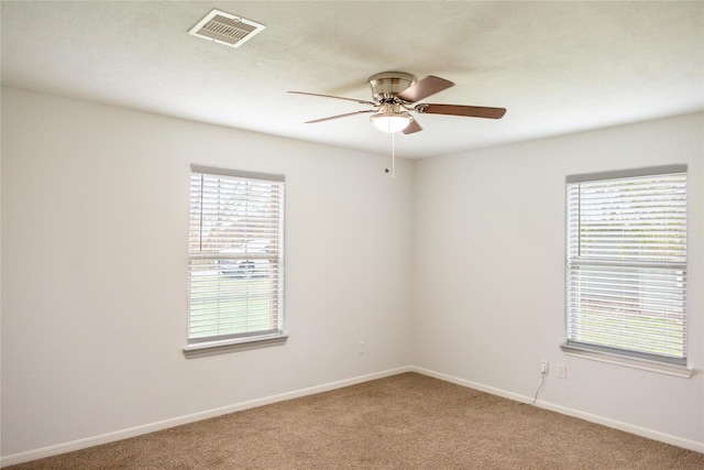 spare room featuring carpet, ceiling fan, and a wealth of natural light