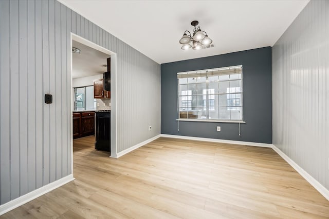 unfurnished dining area with a chandelier and light wood-type flooring