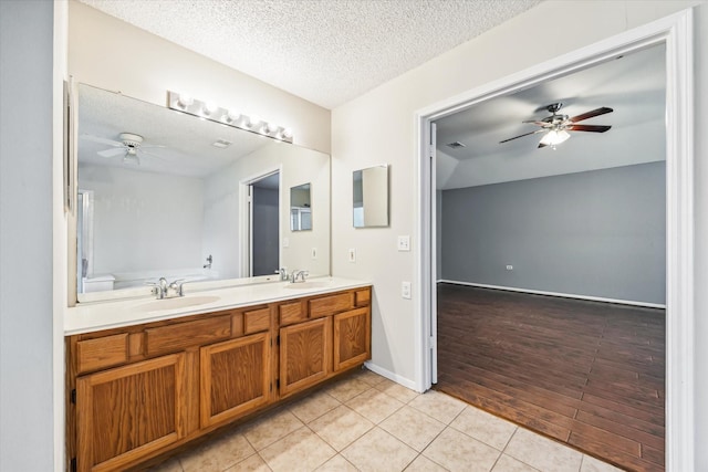 bathroom with tile patterned flooring, vanity, ceiling fan, and a textured ceiling