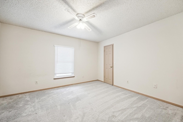 empty room featuring ceiling fan, light colored carpet, and a textured ceiling