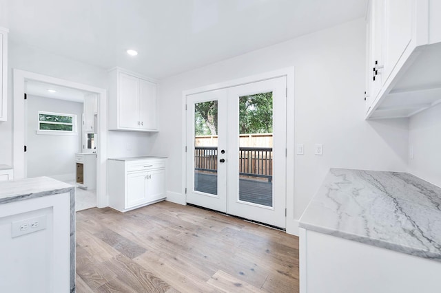 kitchen with white cabinetry, french doors, light hardwood / wood-style floors, and light stone counters