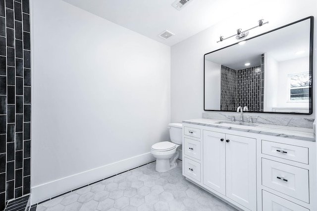 bathroom with tile patterned flooring, vanity, toilet, and a tile shower