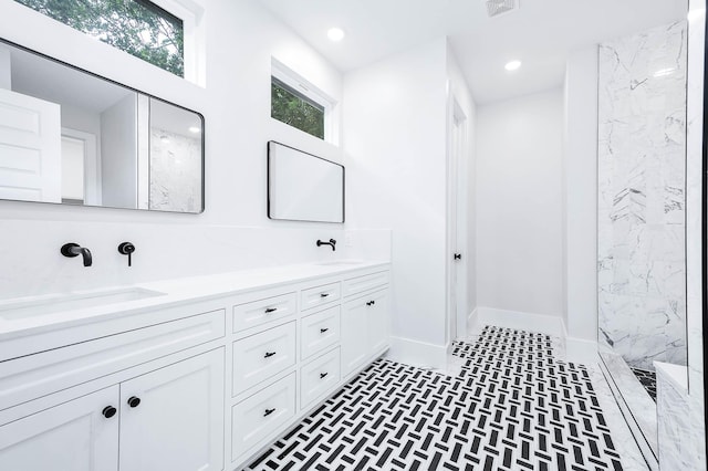 bathroom with a tile shower and vanity