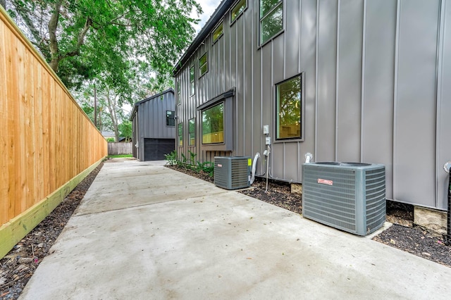 view of side of home with a garage, an outbuilding, a patio, and central AC