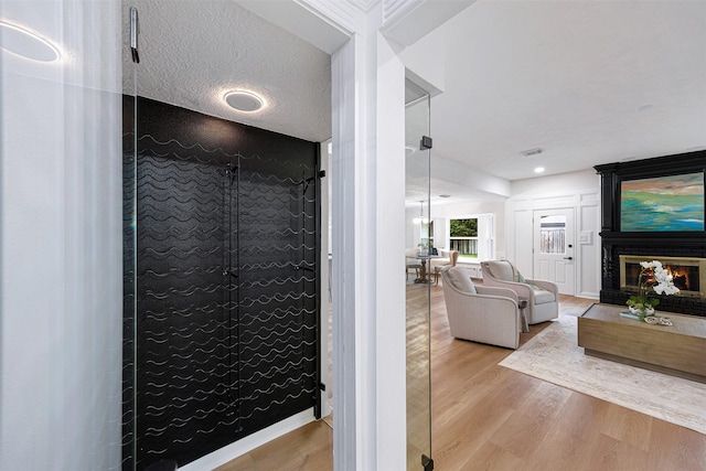 bathroom featuring a fireplace, hardwood / wood-style floors, and a textured ceiling