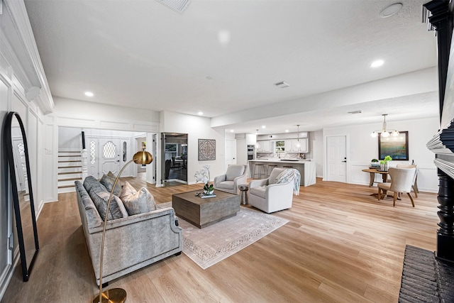 living room featuring a chandelier, light hardwood / wood-style floors, and a brick fireplace