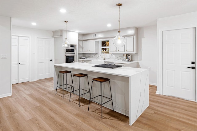 kitchen featuring pendant lighting, a kitchen island, white cabinetry, and light hardwood / wood-style floors