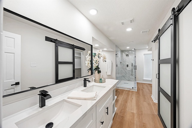 bathroom with a textured ceiling, vanity, hardwood / wood-style flooring, and an enclosed shower