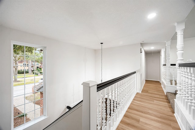 hallway with light hardwood / wood-style flooring and a textured ceiling