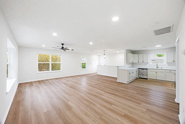 unfurnished living room featuring sink, plenty of natural light, ceiling fan, and light wood-type flooring