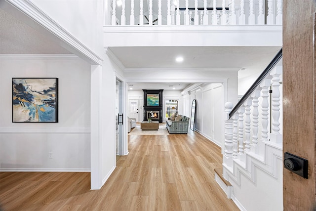 interior space featuring a large fireplace, light hardwood / wood-style floors, and crown molding