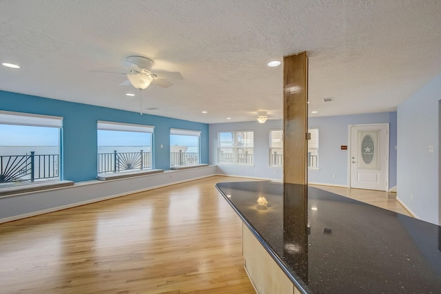 interior space featuring ceiling fan, light hardwood / wood-style floors, and a textured ceiling