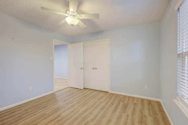 unfurnished bedroom with ceiling fan, a closet, light hardwood / wood-style floors, and a textured ceiling