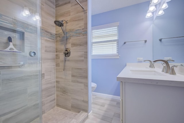 bathroom with a tile shower, vanity, a textured ceiling, and toilet