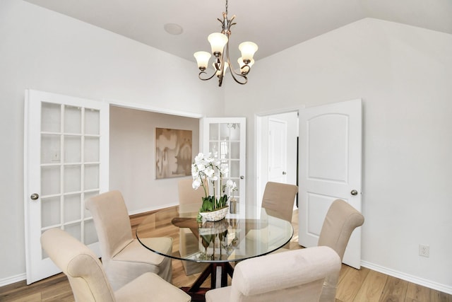 dining space featuring an inviting chandelier, vaulted ceiling, and hardwood / wood-style flooring