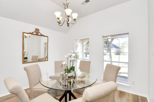 dining room featuring vaulted ceiling, light hardwood / wood-style flooring, and a notable chandelier