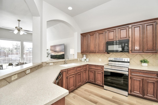 kitchen with backsplash, range with electric cooktop, vaulted ceiling, sink, and light hardwood / wood-style flooring