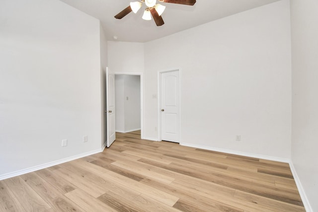 empty room featuring a towering ceiling, light hardwood / wood-style floors, and ceiling fan