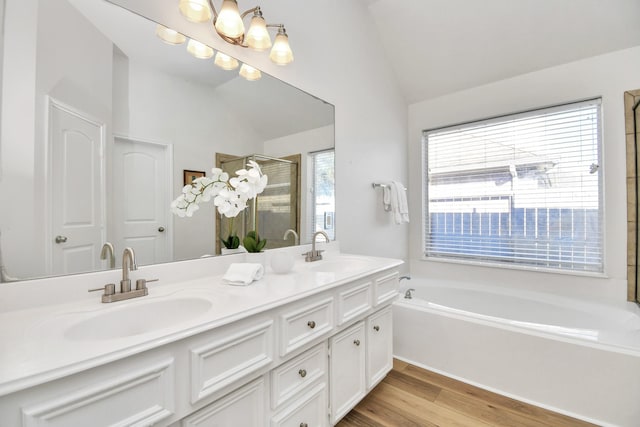 bathroom featuring plenty of natural light, vanity, wood-type flooring, and vaulted ceiling