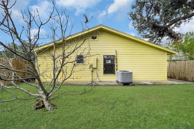 view of side of property featuring central air condition unit and a yard