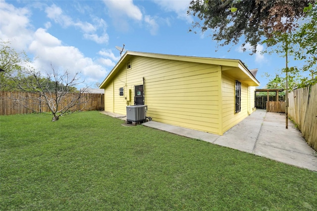 view of side of property with a patio, a yard, and central AC