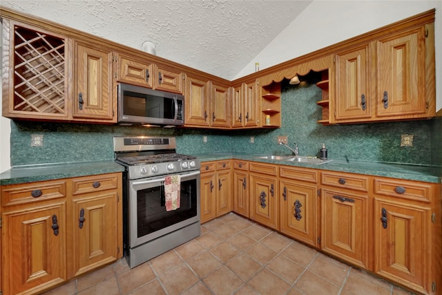 kitchen featuring sink, vaulted ceiling, decorative backsplash, light tile patterned flooring, and stainless steel appliances