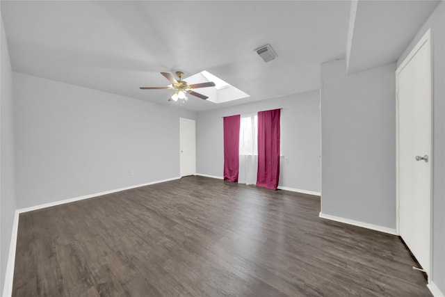 unfurnished room with a skylight, ceiling fan, and dark wood-type flooring