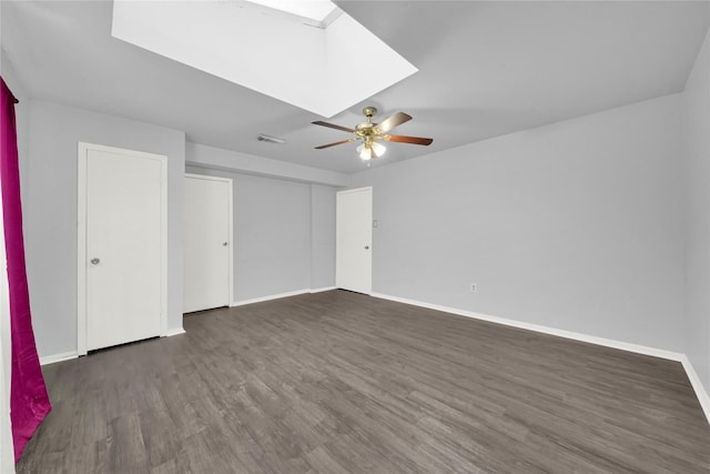 spare room featuring dark hardwood / wood-style floors, ceiling fan, and a skylight