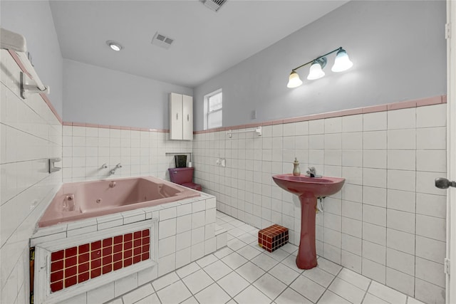 bathroom with tile patterned floors, a bathing tub, and tile walls