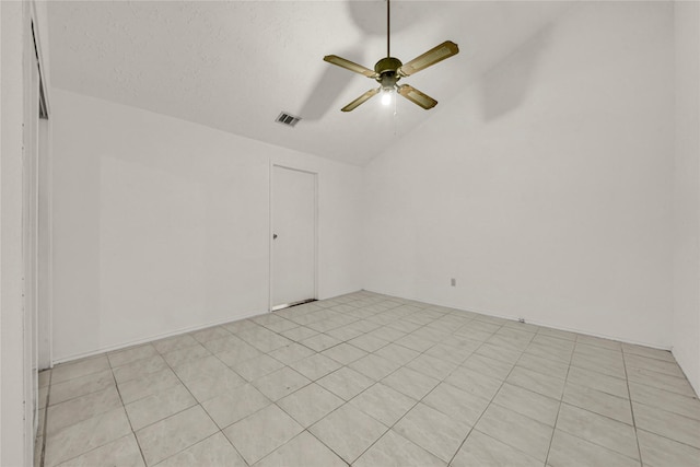 empty room featuring a textured ceiling, ceiling fan, light tile patterned floors, and lofted ceiling