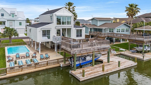 back of property with a swimming pool side deck with water view and a patio