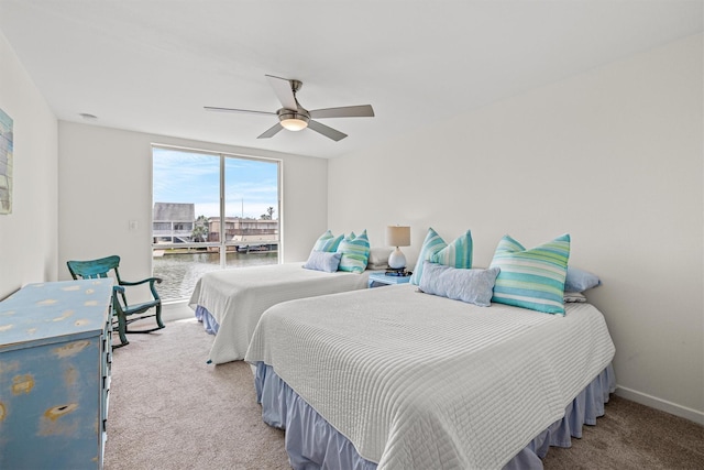 bedroom featuring carpet flooring, ceiling fan, and a water view