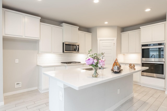 kitchen with a center island with sink, white cabinets, and stainless steel appliances