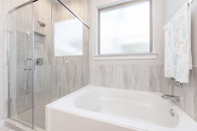 bathroom featuring plenty of natural light and independent shower and bath