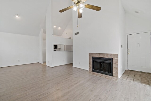 unfurnished living room with ceiling fan, light wood-type flooring, a fireplace, and high vaulted ceiling