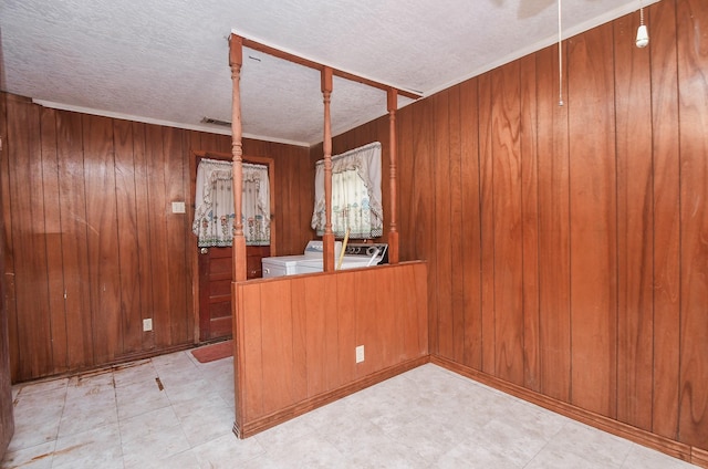 interior space with washing machine and dryer, wood walls, kitchen peninsula, and a textured ceiling