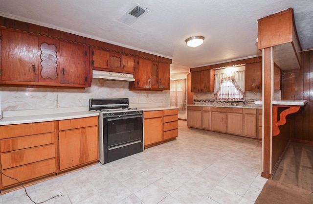 kitchen with decorative backsplash, range, a textured ceiling, and ornamental molding