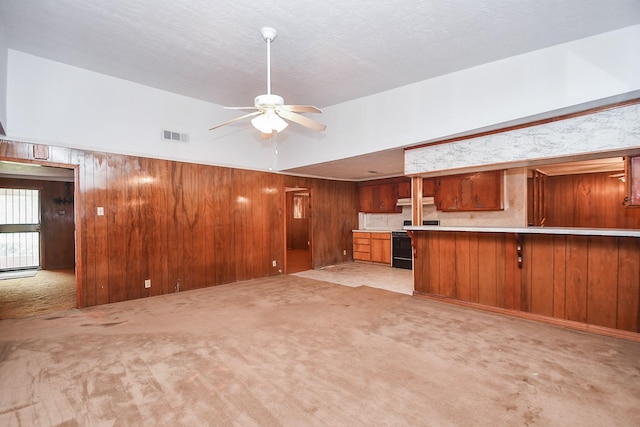 unfurnished living room with light colored carpet, ceiling fan, and wooden walls