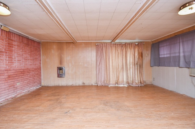 unfurnished room with light wood-type flooring, wooden walls, and heating unit