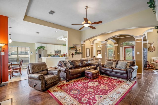 living room featuring ceiling fan, ornate columns, and dark hardwood / wood-style floors