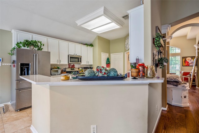 kitchen featuring kitchen peninsula, white cabinetry, light tile patterned floors, and appliances with stainless steel finishes