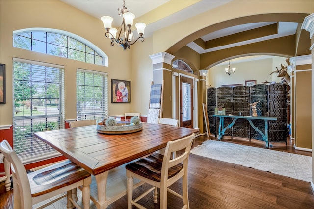 dining area with an inviting chandelier, ornate columns, and dark hardwood / wood-style flooring