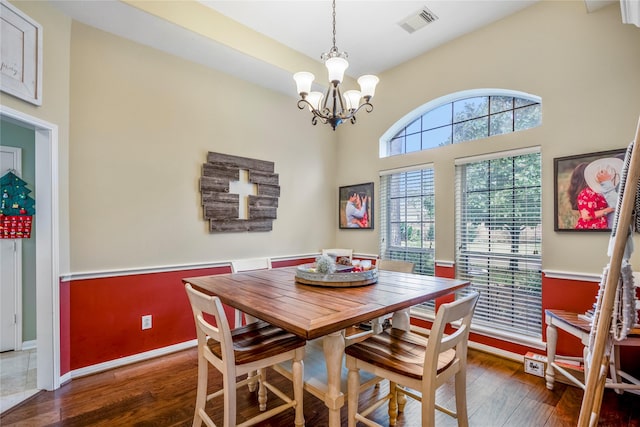 dining area with dark hardwood / wood-style flooring and an inviting chandelier