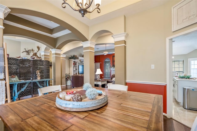 dining space featuring light hardwood / wood-style flooring, a notable chandelier, and ornate columns