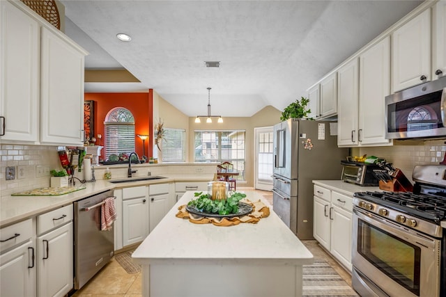 kitchen featuring kitchen peninsula, sink, tasteful backsplash, a kitchen island, and stainless steel appliances