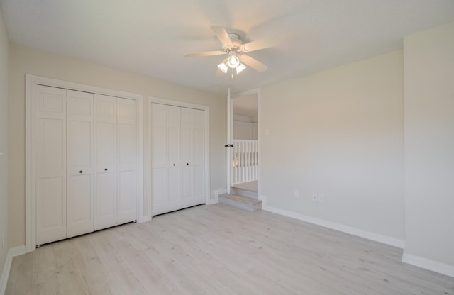 unfurnished bedroom with two closets, light hardwood / wood-style flooring, and ceiling fan