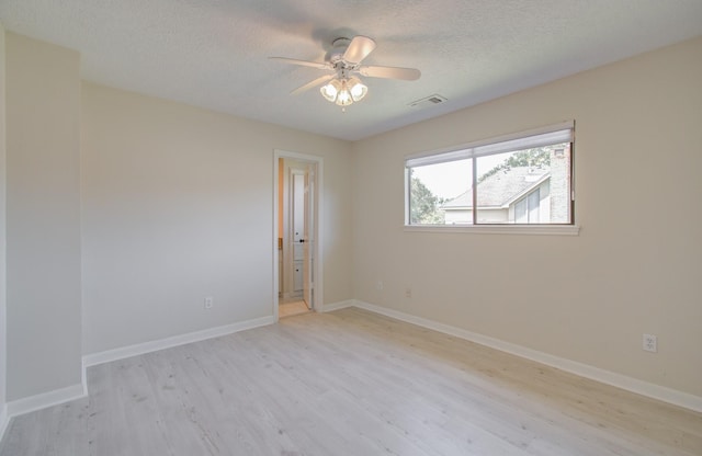 empty room with a textured ceiling, light wood-type flooring, and ceiling fan