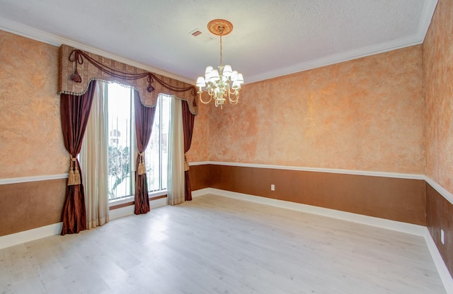 unfurnished room featuring a chandelier, a textured ceiling, light hardwood / wood-style flooring, and ornamental molding