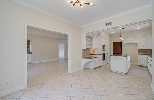 kitchen with tasteful backsplash, stainless steel appliances, a kitchen island, decorative light fixtures, and white cabinetry