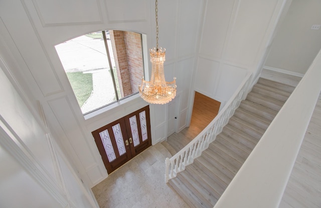 foyer featuring french doors, light hardwood / wood-style flooring, and a notable chandelier